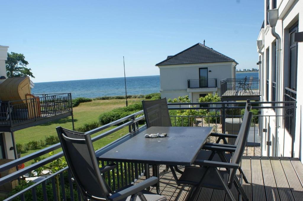a table and chairs on a balcony with the ocean at Strandresidenz Vogelflug App 13 in Fehmarnsund