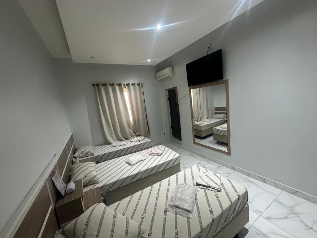 a room with two beds and a large mirror at Hotel Marajá Bela Vista - Próximo ao Shopping Frei Caneca in Sao Paulo
