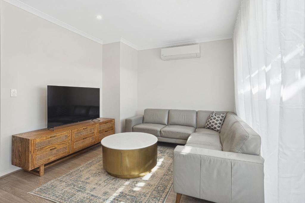 a living room with a couch and a table and a tv at Tranquil Tree Views 2 Bedroom 2 Bathroom Apartment in Perth