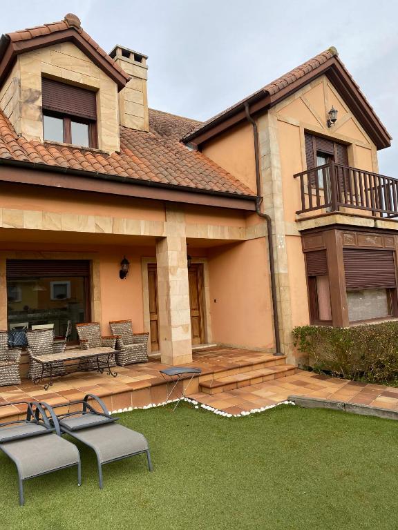 a house with a patio with two chairs and a table at Casa Santiago in Argoños