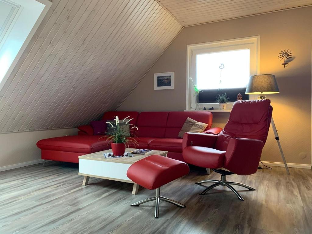 un salon avec un canapé rouge et deux chaises dans l'établissement Dornieden, à Fehmarn