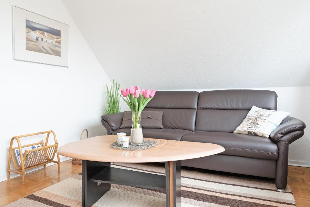 a living room with a couch and a table with flowers at Haus Hüttmann Sommerbrise in Gremsmühlen