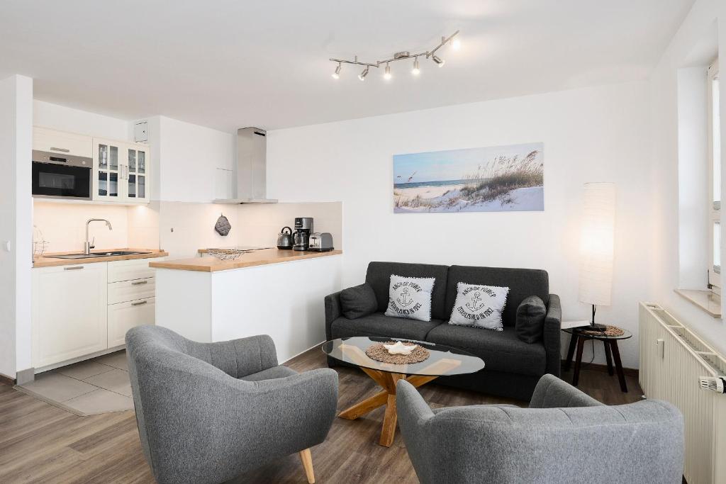 a living room with a couch and chairs and a table at Promenade 27 Koje 23 in Stakendorfer Strand