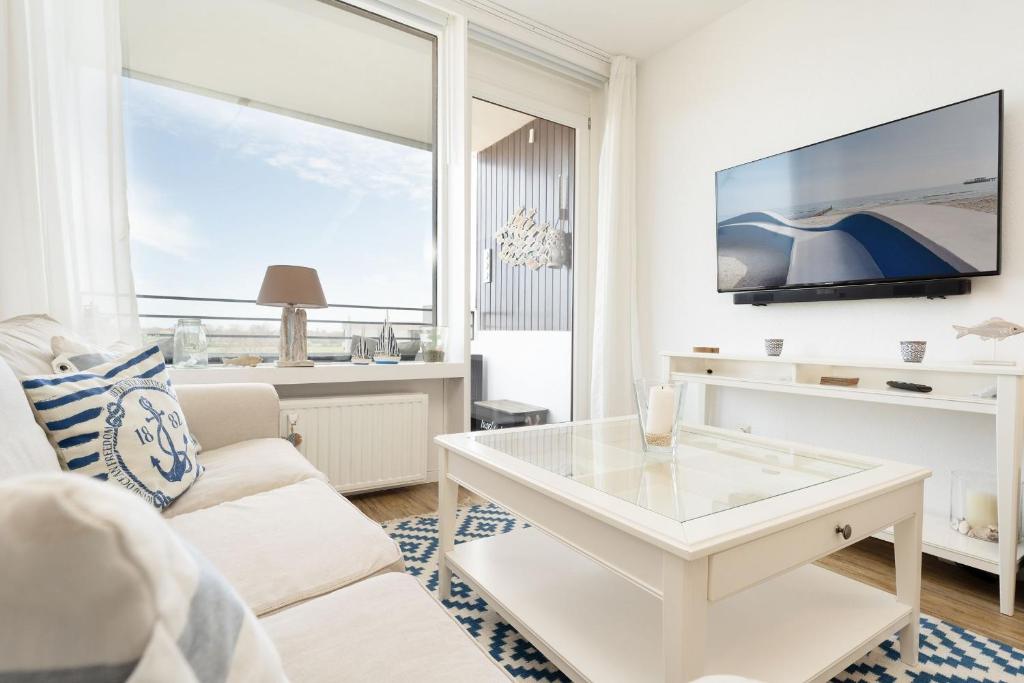 a living room with a white couch and a tv at Haus Meeresblick Ankerplatz 84 in Kellenhusen