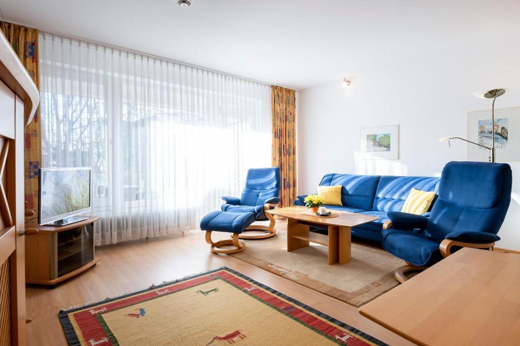 Una sala de estar con un sofá azul y una mesa. en Waldstraße 2 Windrose Kellenhusen, en Kellenhusen