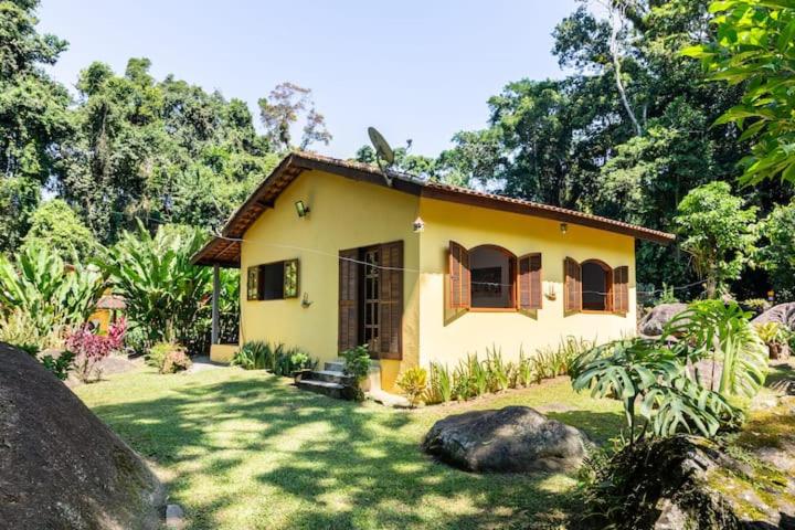 une petite maison jaune dans une cour dans l'établissement Recanto da Margo 1, casa com acesso a cachoeira, à Parati