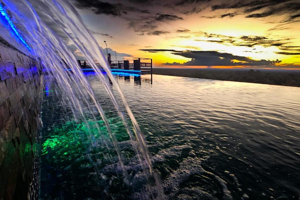 a fountain in the water with a sunset in the background at Cabañas Balcones de Nogolí II - San Luis in Hipólito Yrigoyen