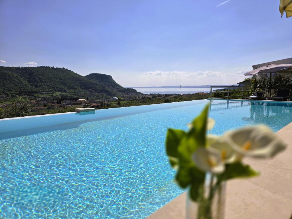 een vaas met bloemen naast een zwembad bij Relais Villa Olivi in Costermano