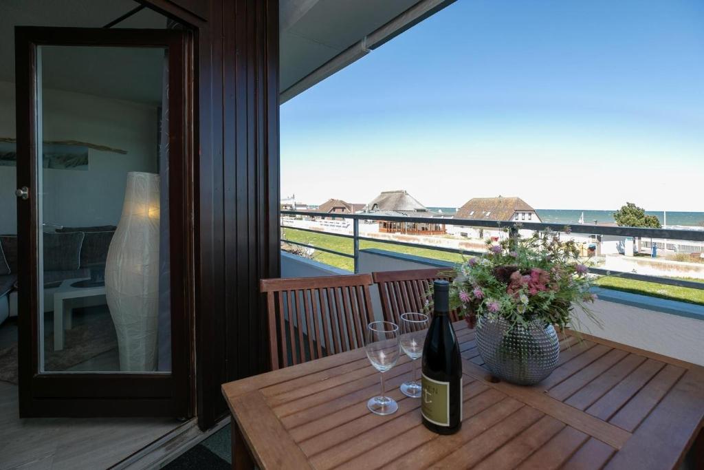 ダーメにあるStrandhotel Dahme TraumMeerBlickの木製テーブル(ワインボトル、グラス付)