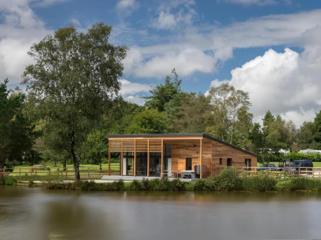 a small wooden house next to a body of water at Silver Birch in Winkleigh