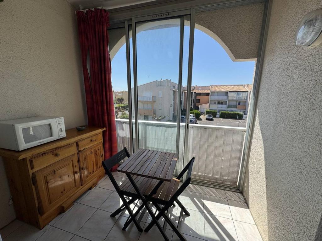 d'un balcon avec une table et des chaises et un four micro-ondes. dans l'établissement T2 Mezzanine près de la plage avec parking au Cap d'Agde - FR-1-749-99, au Cap d'Agde