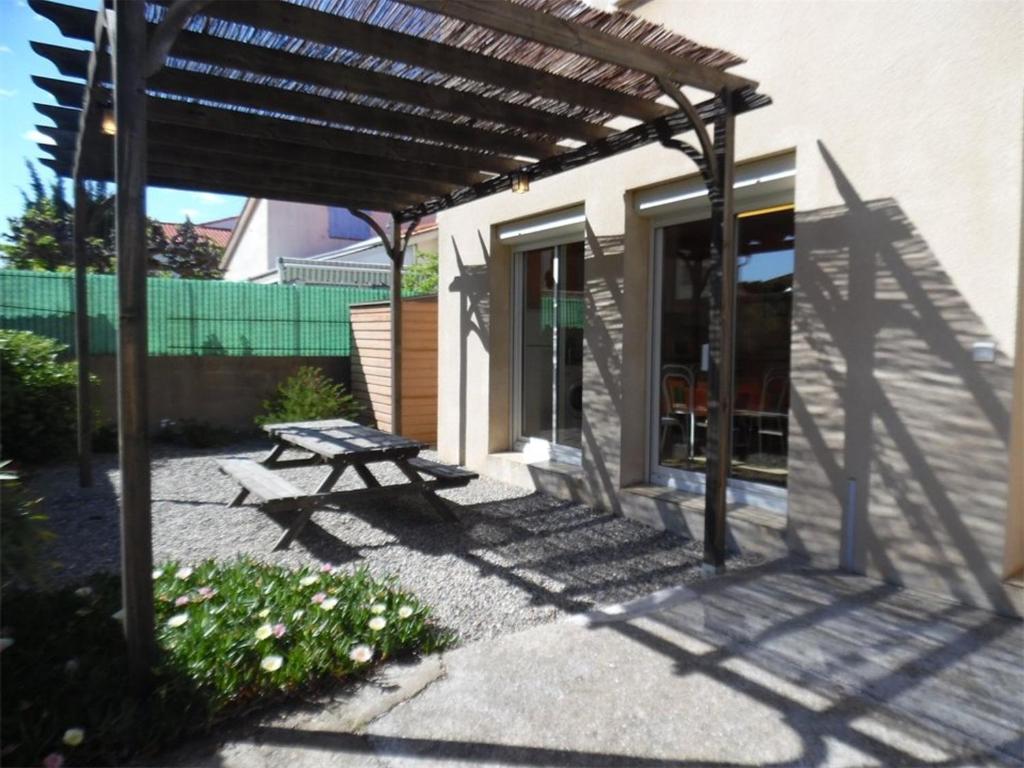- une table de pique-nique sous une pergola dans un patio dans l'établissement Appartement T2 calme avec terrasse et parking - 400m de la plage - FR-1-750-85, à Canet