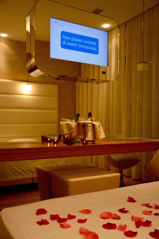 a room with a bed and a television with roses on a table at AmbientHotels Panoramic in Rimini