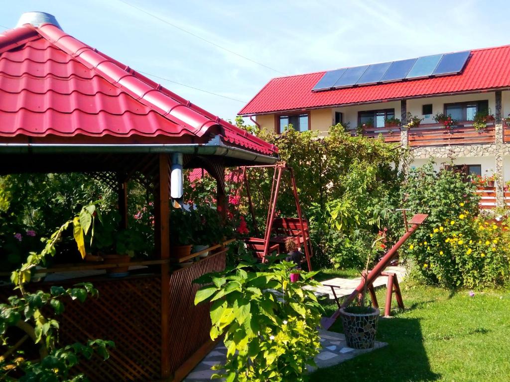 a garden with a gazebo with a red roof at Pensiunea Dana in Horezu