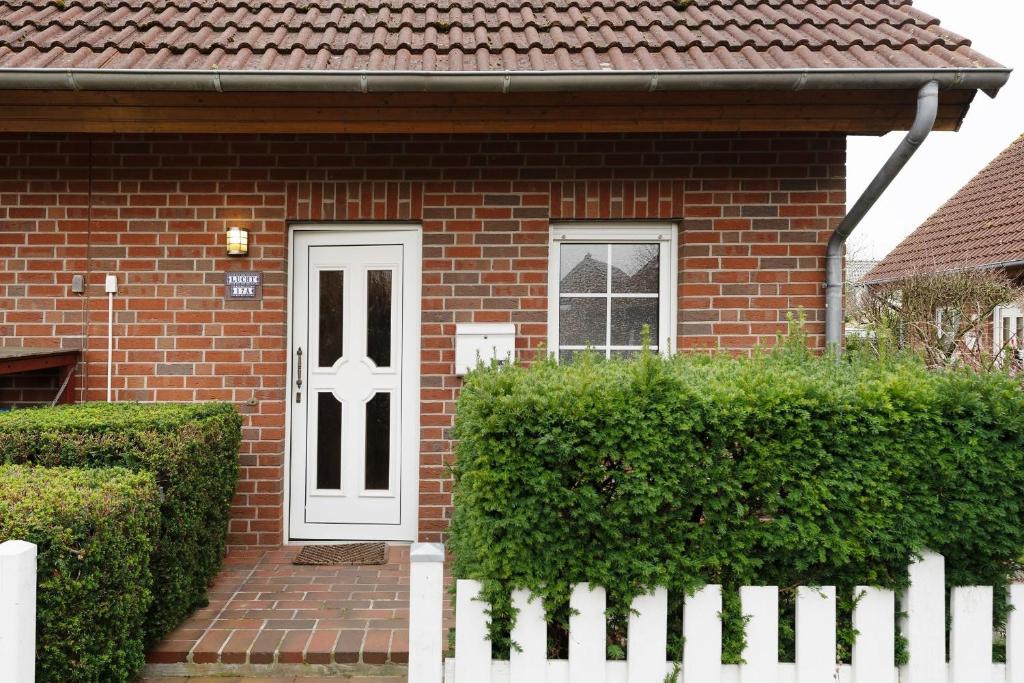 a brick house with a white door and a white fence at Ferienhaus 17a in Kellenhusen