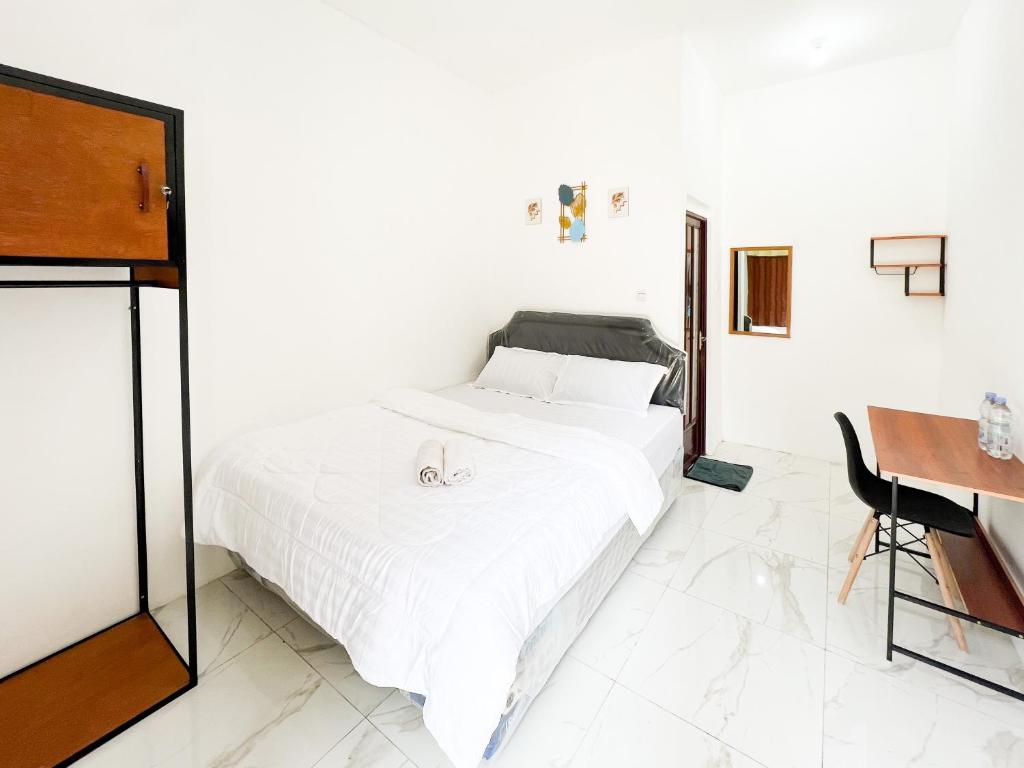 Un dormitorio blanco con una cama y un escritorio. en Graha Indah Ngagel Surabaya RedPartner, en Surabaya
