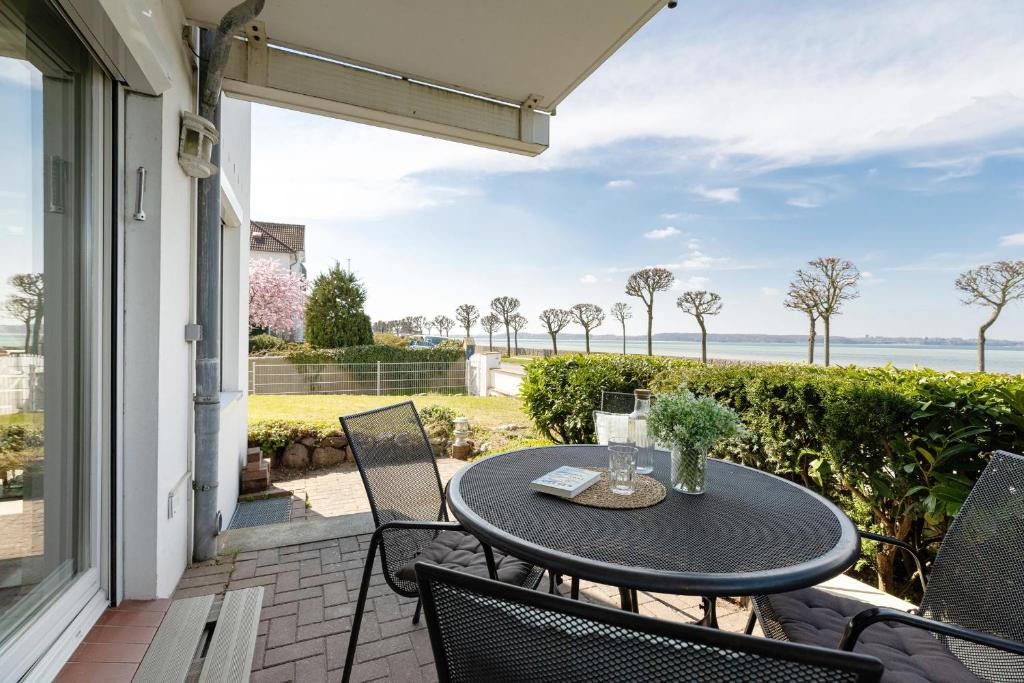 a patio with a table and chairs and the ocean at Villa Fördestrand Sehpferdchen in Laboe