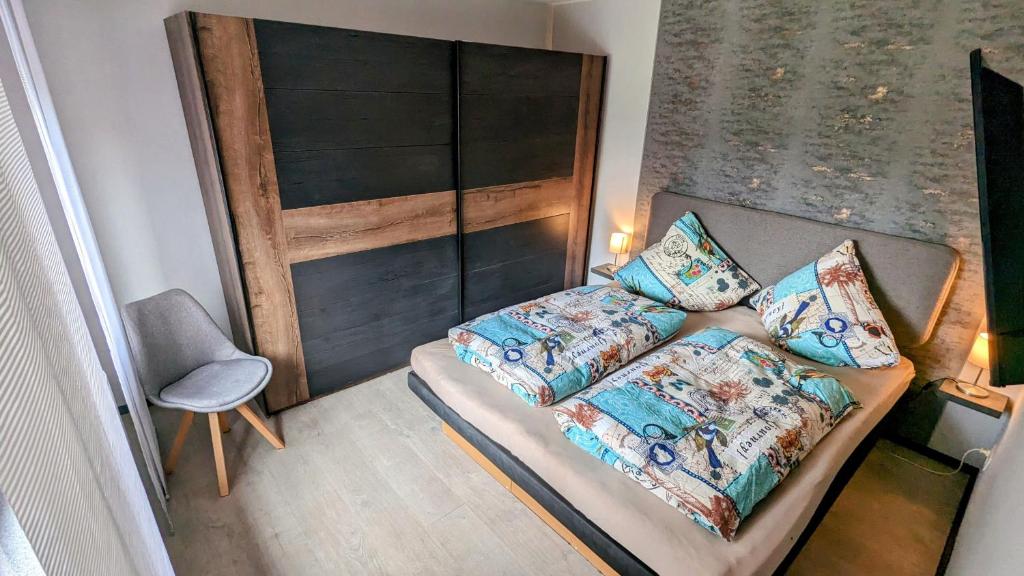 Un pequeño dormitorio con una cama y una silla. en Ferienhaus Meer & Mehr, en Wilhelmshaven