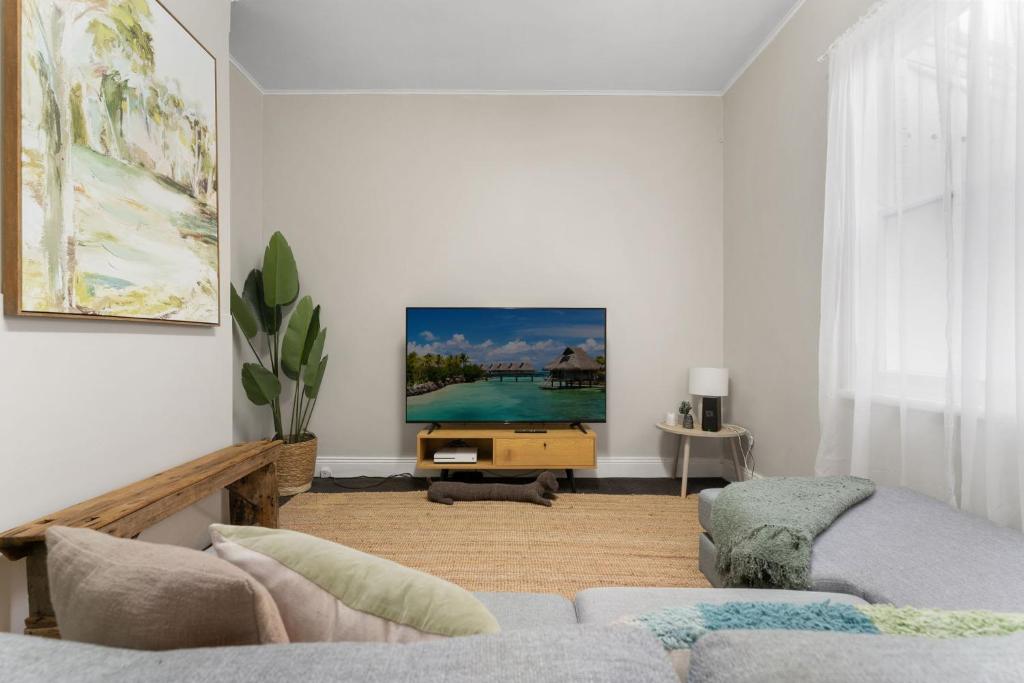 Una sala de estar con un sofá y un televisor. en William House - Heart of Bathurst - Sleeps 6, en Bathurst
