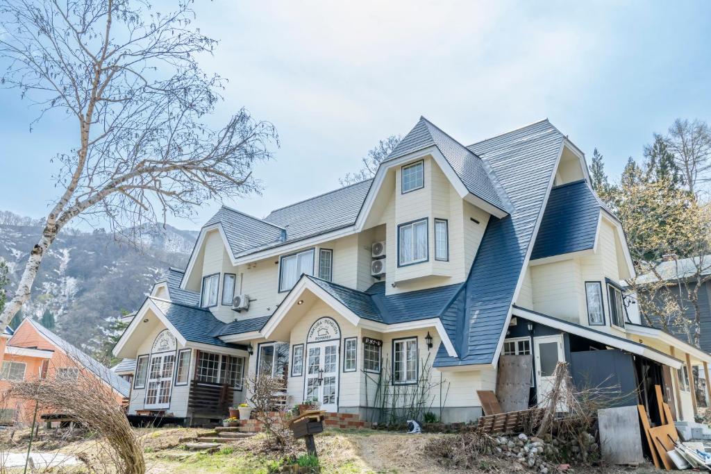 a large house with a blue roof at Pension Bonnard in Hakuba