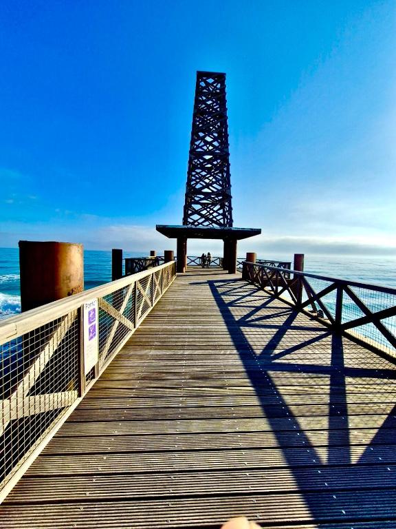 une promenade en bois avec un phare sur la plage dans l'établissement Les portes de la Plage, à Port-Leucate