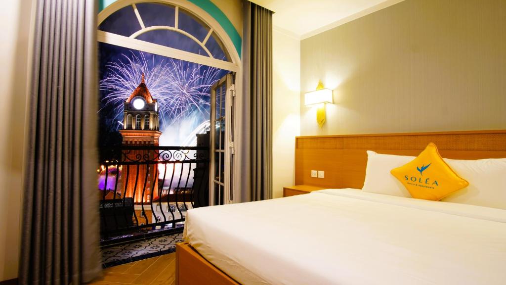 a bedroom with a bed and a window with a picture of a tower at Soléa Hotel & Serviced Apartment Sunset Town Phu Quoc in Phu Quoc