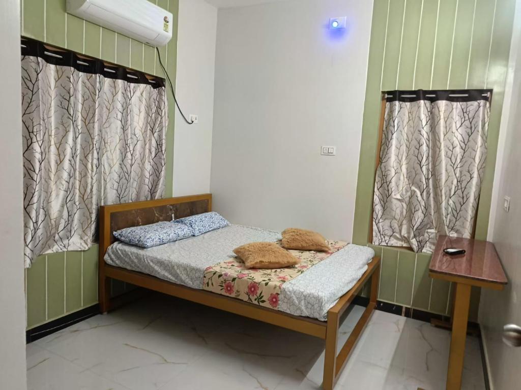 a small bed in a room with two windows at Little Hearts recidency in Āvadi
