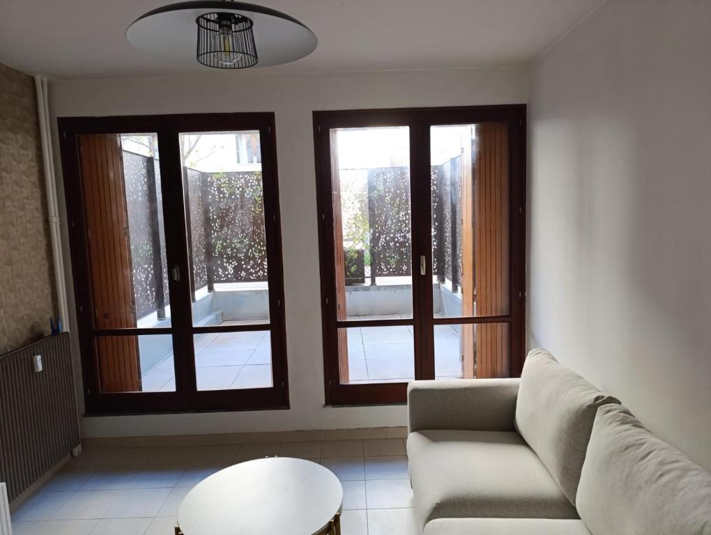 un salon avec un canapé et deux fenêtres dans l'établissement Studio Cosy rue Thiers avec Terrasse, à Avignon