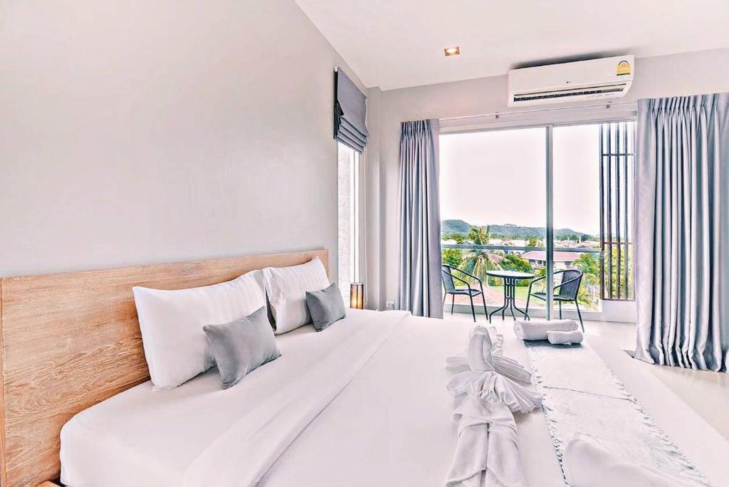 a bedroom with a large bed and a large window at Lemonade Phuket Hotel -SHA Plus in Chalong