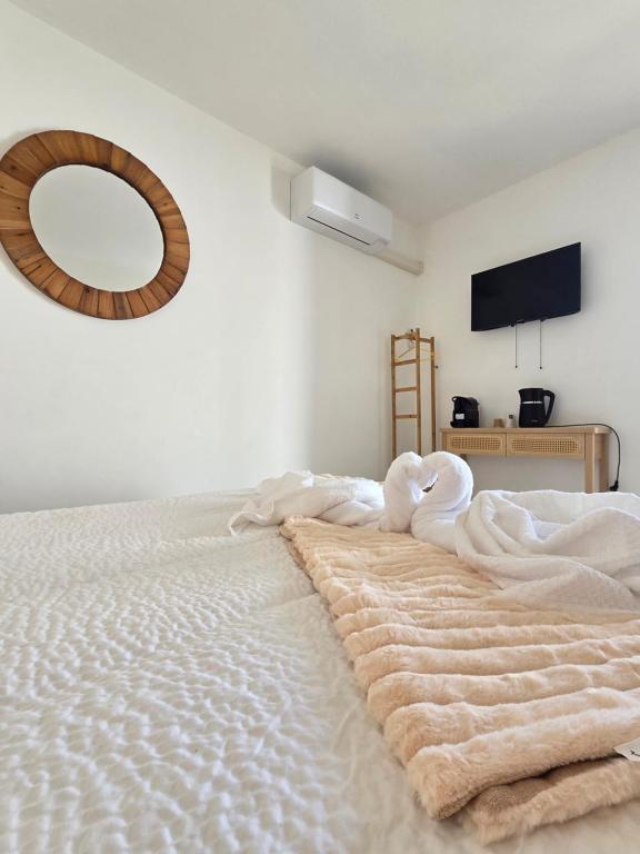 une chambre avec un lit avec des draps blancs et un miroir dans l'établissement Les chambres des Saladelles, à La Celle-sous-Gouzon