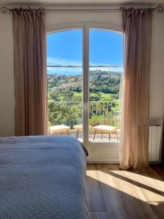 une chambre avec un lit et une grande fenêtre dans l'établissement Villa nichée sur golf & piscine, à Sainte-Maxime