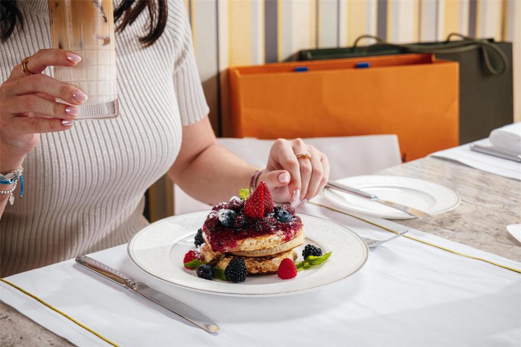 a woman cutting a dessert with a strawberry on a plate at Kempinski Hotel Mall of the Emirates, Dubai in Dubai