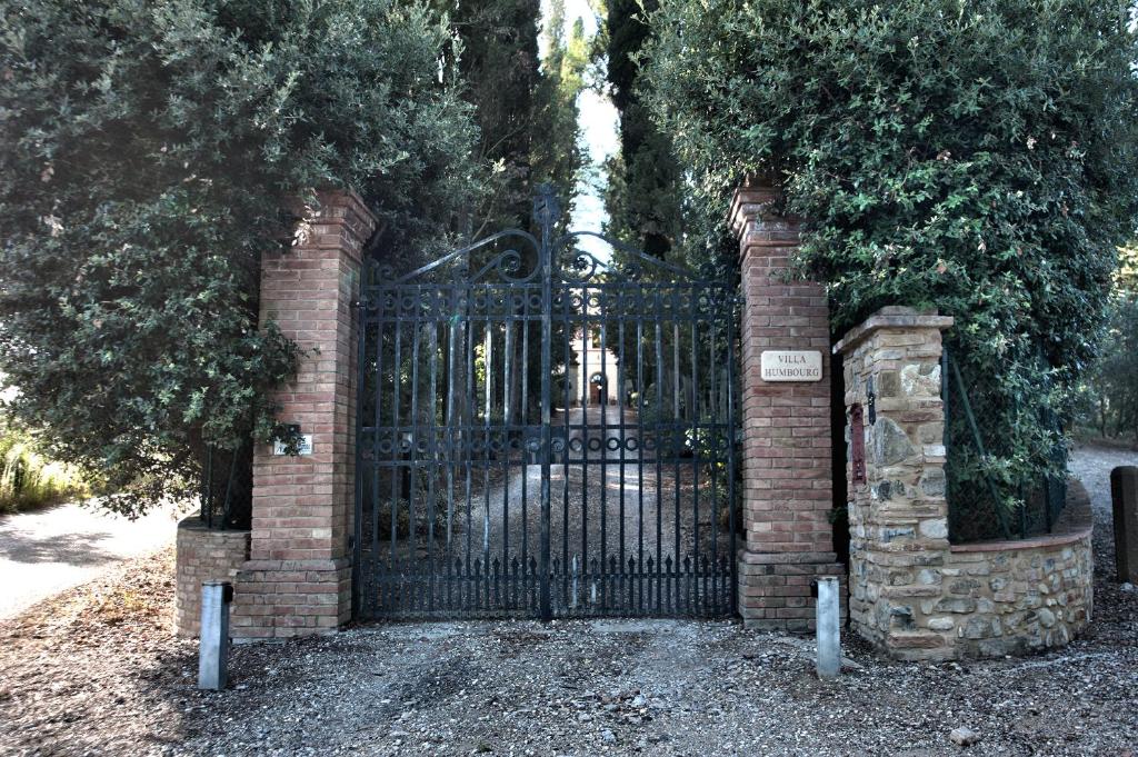 a black gate with a brick pillar and tree at Villa Humbourg in Certaldo