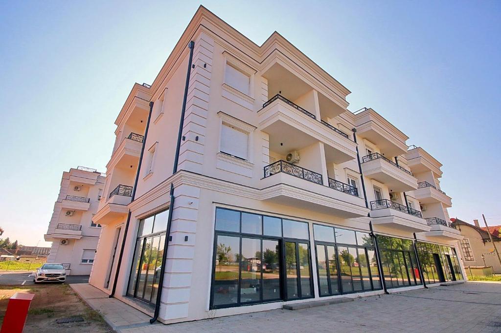 a large white building with windows on a street at White Diamond in Palić