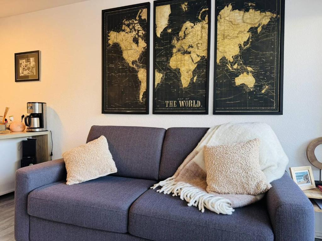 un salon avec un canapé bleu avec une carte au mur dans l'établissement Ty Cardinaux, grand studio cabine, terrasse, jardin, tennis, à Quiberon