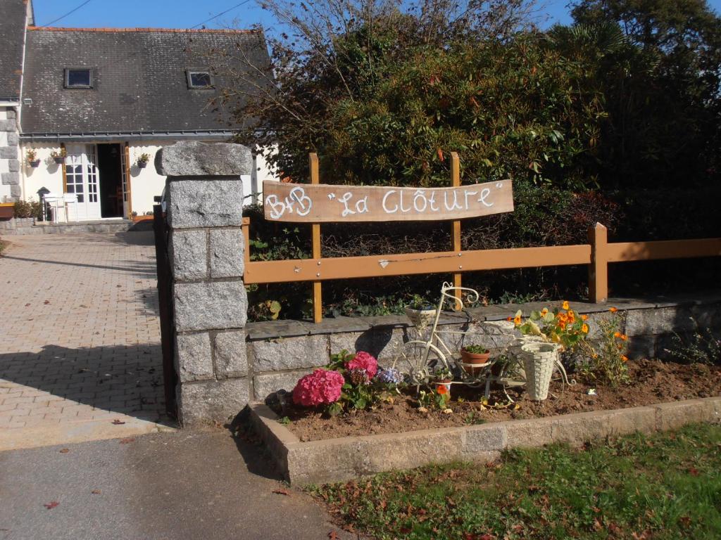 ein Schild für ein Cottage mit Blumen im Garten in der Unterkunft La Clôture in Lanouée