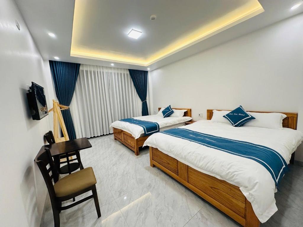 a hotel room with two beds and a desk at New Sun Hotel in Dồng Văn