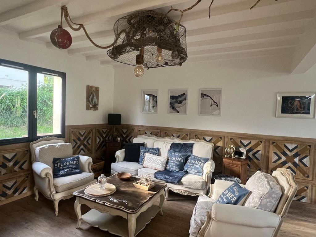 un salon avec un canapé, des chaises et un lustre dans l'établissement Les Hauts d'Omaha, à Saint-Laurent-sur-Mer