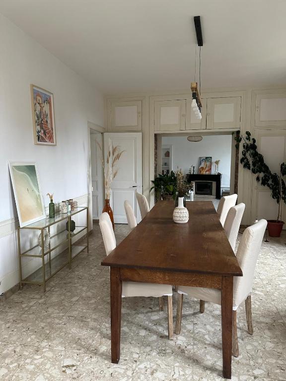 une salle à manger avec une table en bois et des chaises blanches dans l'établissement Maison style Haussmannien centre ville, à Gray