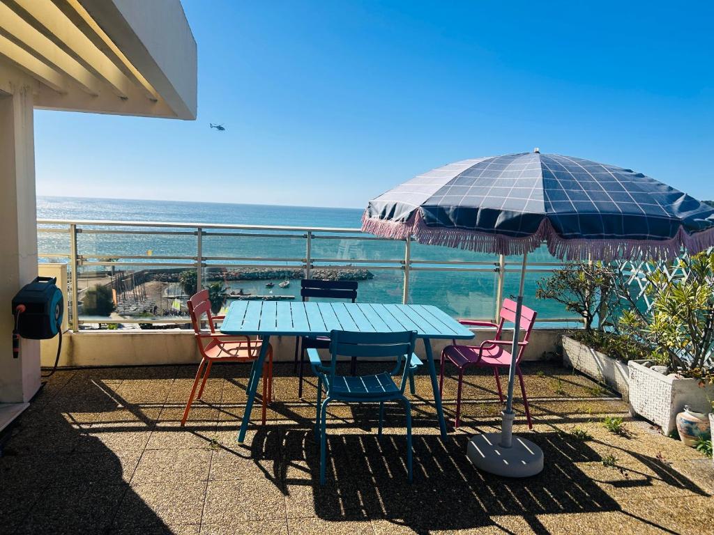 - une table avec des chaises et un parasol sur le balcon dans l'établissement Appartement Menton front de mer au dernier étage de 95M2 avec Terrasse de 70M2, à Roquebrune-Cap-Martin