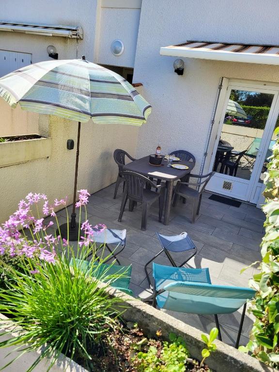 un patio avec une table, des chaises et un parasol dans l'établissement Studio Bord de mer avec terrasse, à Saint-Georges-de-Didonne