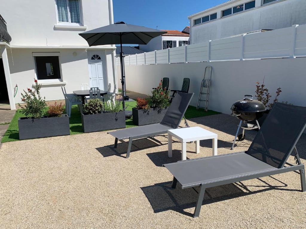 un patio avec deux chaises, une table et un parasol dans l'établissement Maison familiale, à La Tranche-sur-Mer