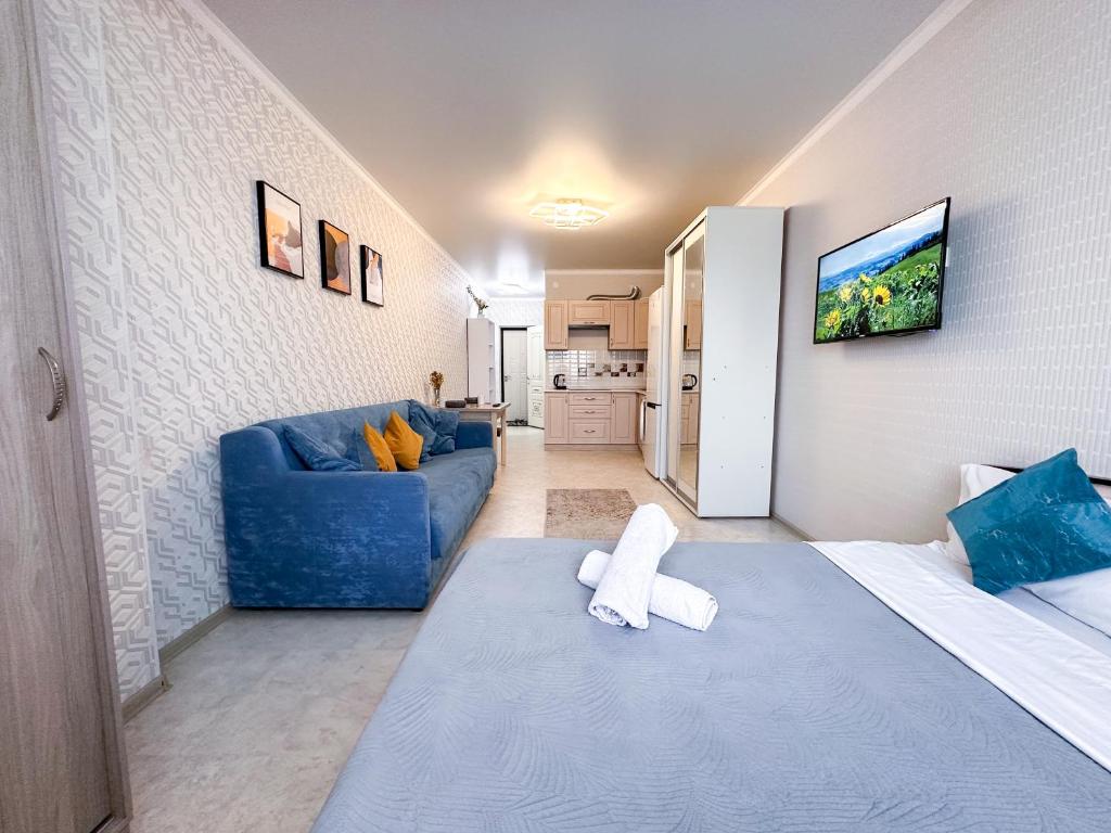 a living room with a blue couch and a blue couch at Уютная студия в центре города in Almaty