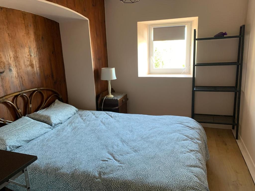 une chambre avec un lit avec une couverture bleue et une fenêtre dans l'établissement La petite maison dans le Sidobre, à Fontrieu