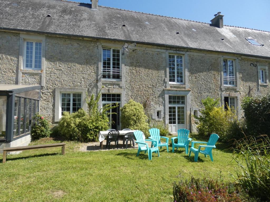 een stenen huis met stoelen en een tafel in de tuin bij Gîte de la Ferme Feugère in Barbeville