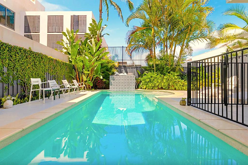 Una piscina en un patio con sillas y un edificio. en Fletcher Lane Boutique Stay Byron Central, en Byron Bay