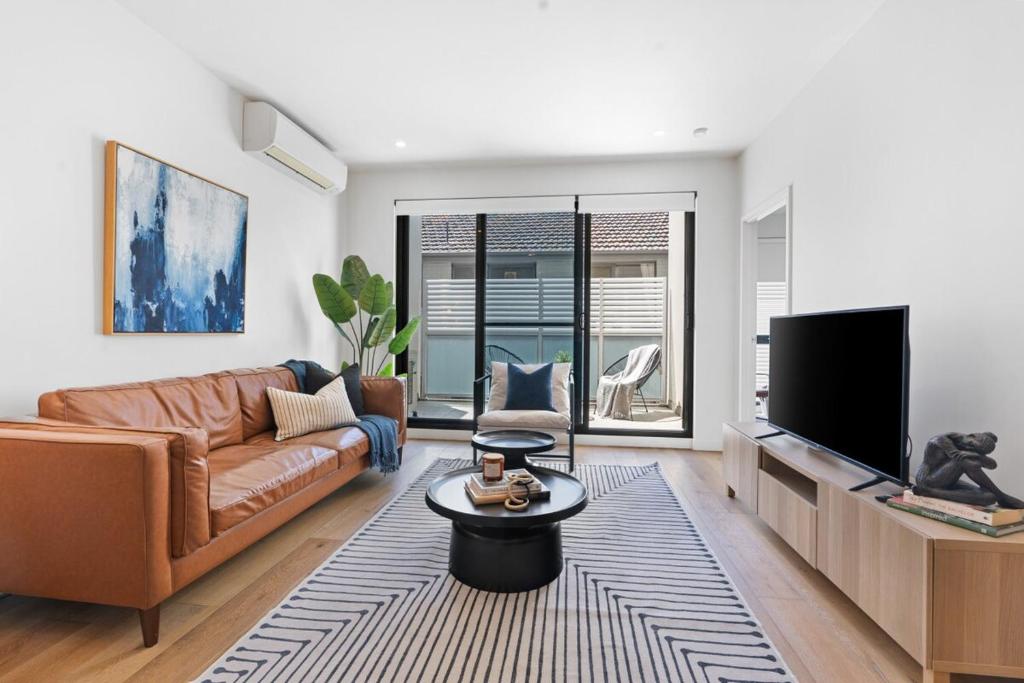 a living room with a couch and a tv at Urban Living at Its Best in Carnegie