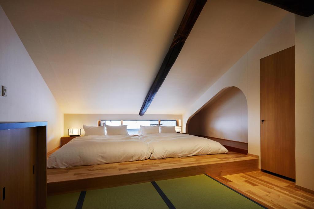a bedroom with a large bed with a wooden floor at Enso Machiya in Kyoto