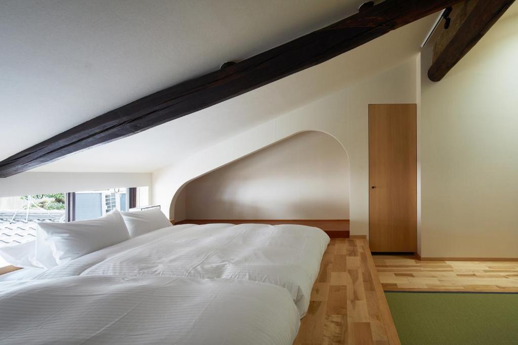 a bedroom with a white bed and a large window at Enso Machiya in Kyoto