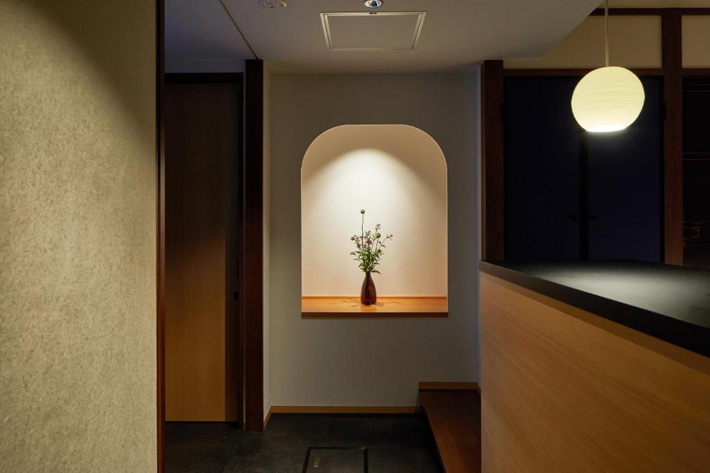 a room with a vase with flowers in a niche at Enso Machiya in Kyoto